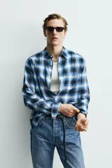 Camisa de corte regular fit confeccionada en tejido fluido de algodón y viscosa. Presenta un diseño de cuadros, cuello solapa, manga larga con puños abotonados, bolsillo en el pecho y cierre frontal con botones.