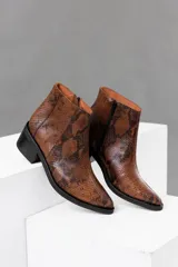 Botas cortas de cuero vacuno color marrón con estampado de piel de serpiente, taco de madera foliado en cuero y cierre lateral con cremallera.