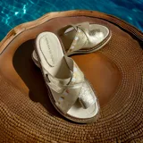 Sandalias planas doradas Carolina de Cunto modelo Noa, con tiras cruzadas de cuero texturizado y detalles pintados a mano.