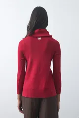 Polera de cuello alto holgado, manga larga y diseño de tejido fino con aberturas laterales en el ruedo.