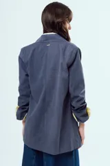 Blazer de corte oversize color azul, con solapas clásicas, cierre de doble botonadura frontal y bolsillos ribeteados.