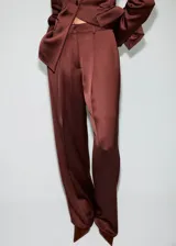 Pantalón largo de tiro medio en tejido satinado color marrón, con diseño de pernera recta, trabillas para cinturón, pinzas delanteras, bolsillos laterales y bolsillos de ribete en la parte posterior. Cierre frontal oculto con botón, gancho y cremallera.
