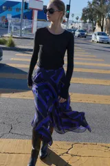 Falda midi de corte asimétrico con diseño cruzado en el delantero y aberturas. Presenta un estampado geométrico en tonos azul, negro y beige, con forro interior y cierre trasero con cremallera oculta.