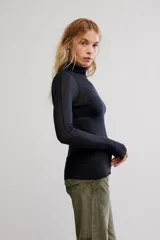 Remera de punto fino semitransparente, color negro, de calce ajustado, con cuello alto, mangas largas y orificios para los pulgares en los puños.