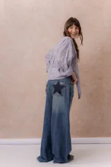 Jean wide leg de tiro alto y lavado azul desgastado, con cinco bolsillos y detalles de estrellas en denim oscuro con tachas metálicas en los bolsillos traseros.