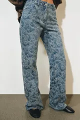Pantalón jean tiro alto de corte flare con diseño jacquard estampado completo, cinco bolsillos, trabillas para cinto y cierre frontal con cremallera y botón metálico.