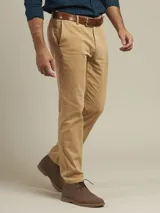 Pantalón de vestir color beige, de corte recto, con bolsillos laterales y traseros. Se ajusta a la cintura con cinturón de cuero marrón.