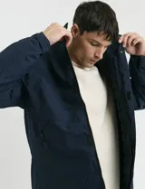 Campera 2 en 1 azul marino con capucha desmontable, cierre frontal con solapa de botones a presión y bolsillos laterales con cierre.
