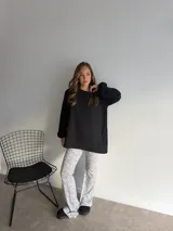 Pantalón de corte oxford con estampado de pequeñas manchas negras sobre fondo blanco. Presenta una silueta ajustada en la parte superior y acampanada hacia el ruedo.