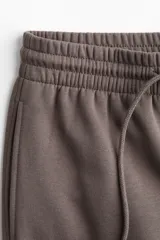 Pantalón deportivo de tiro alto confeccionado en felpa de mezcla de algodón con interior cepillado. Presenta cintura elástica con cordón de ajuste, bolsillos laterales al bies y puños elásticos en los bajos.