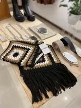 Bufanda tejida a mano en crochet, con capucha y diseño de cuadrados en tonos beige, marrón y negro.