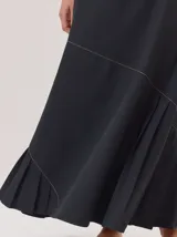 Falda larga color marrón, con diseño de corte asimétrico y tablas en el ruedo que aportan movimiento. Confeccionada en una mezcla de algodón y tencel.