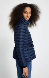 Campera puffer de corte entallado con diseño capitoneado, cuello alto y cierre frontal. Presenta ajuste con lazo en la cintura y bolsillos laterales con cierre.