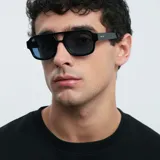 Lentes de sol de aviador oversize, con montura negra y lentes azules polarizadas.