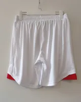 Short de fútbol Umbro del Club Nacional de Football, modelo Home 2025. Diseño en color azul con detalles en rojo en los laterales y el escudo del club junto al logo de la marca.