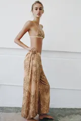 Pantalón de tiro medio con cintura elástica y bajo abullonado. Presenta un diseño con hilo metalizado y aplicaciones de abalorios y lentejuelas en toda la prenda.