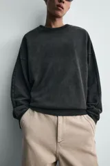 Sudadera de corte relaxed fit confeccionada en tejido de algodón con interior de rizo. Presenta cuello redondo, manga larga y acabados en rib, con un acabado de efecto lavado que le otorga una apariencia única.