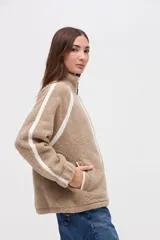 Campera de sherpa color marrón con diseño capitoneado, cierre frontal completo y detalles en color blanco. Presenta cuello alto, bolsillos laterales y puños elásticos.