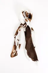 Pañuelo de tela suave con estampado de manchas marrones sobre fondo blanco, de diseño rectangular y acabado fluido.