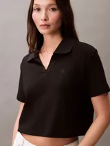 Remera tipo chomba cropped color negro, de algodón acanalado, con cuello polo, cartera abierta y logo bordado en el pecho.