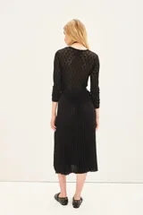 Falda midi plisada de color negro, con cintura elástica para un ajuste cómodo.