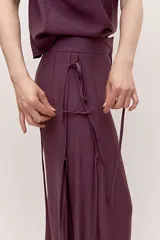 Pantalón de calce amplio y caída suelta, color bordó, con cintura alta y detalle de tiras laterales. Su silueta es oxford.