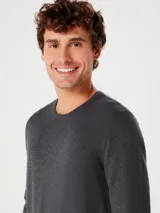 Buzo de punto para hombre en color gris oscuro, con cuello redondo, manga larga y terminaciones acanaladas en puños y cintura.