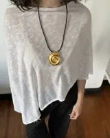Poncho liviano de tejido rústico en color blanco, de corte asimétrico y diseño holgado.