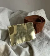 Cinturón de cuero marrón con hebilla rectangular dorada de alpaca.