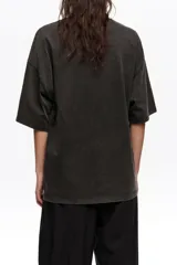 Remera oversize color blanco crudo, confeccionada en algodón, con cuello redondo y mangas cortas. Presenta un estampado frontal en color rojo de un jarrón con flores y el logo de la marca en caligrafía.