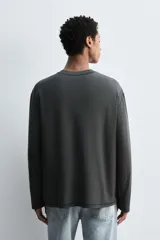 Camiseta relaxed fit de manga larga color gris oscuro, confeccionada en tejido compacto de algodón. Presenta cuello redondo y costuras con efecto revés.