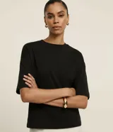 Blusa básica de corte oversized confeccionada en malla de algodón, con cuello redondo y mangas cortas con sisa desplazada.
