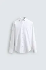 Camisa de corte regular fit confeccionada en tejido de algodón con textura. Presenta cuello italiano, cierre frontal con botones y mangas largas con puños abotonados.