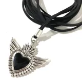 Collar con dije de corazón negro con alas plateadas, engarzado en tiento de cuero negro.