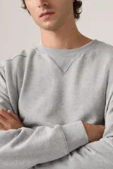 Buzo de cuello redondo con detalle de costura triangular en el escote, confeccionado en algodón con diseño de calce relajado y puños y ruedo acanalados.