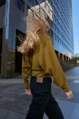 Jersey de punto color mostaza con cuello barco, manga larga con sisa ancha y detalle de cinturón fino integrado en la cintura.