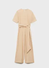 Mono largo de diseño recto, color beige, con cuello redondo, mangas cortas y cierre de botón en la parte posterior. Incluye un cinturón integrado con hebilla del mismo tejido para ajustar a la cintura.