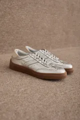 Zapatilla urbana de diseño clásico, color bordó, confeccionada en una combinación de cuero y gamuza. Presenta cordones al tono, suela de goma color caramelo y detalle de marca grabado en dorado en el lateral.