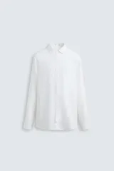 Camisa de corte regular fit confeccionada en tejido de lino, con cuello solapa, manga larga con puños abotonados y cierre frontal de botones.