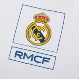 Remera blanca de algodón con cuello redondo y mangas cortas. Estampado en el pecho con el escudo del Real Madrid y las siglas RMCF.