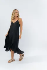 Vestido negro midi con tirantes finos y escote en V. Diseño fluido con bajo asimétrico.