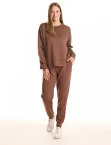 Buzo deportivo de cuello redondo, con hombros caídos y mangas largas con puños. Presenta costuras decorativas tipo pespunte en la parte frontal y en las mangas, con un diseño de ruedo recto y tajos laterales.