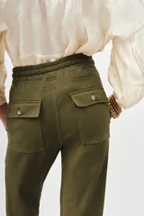 Pantalón tipo babucha de gabardina elastizada, color negro, con cintura elástica ajustable mediante cordón, puños en los tobillos, bolsillos diagonales frontales y bolsillos traseros con solapa y botón.