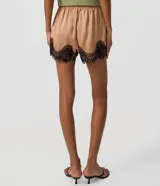 Short de satén color beige con acabado brillante, corte holgado, cintura elástica y detalle de encaje floral negro en el bajo.