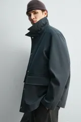 Chaquetón de corte relajado confeccionado en tejido técnico con mezcla de algodón. Presenta cuello solapa, cierre frontal con cremallera oculta por solapa con botones a presión, bolsillos de plastrón con solapa en la cadera y forro interior a contraste.
