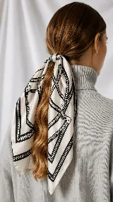 Pañuelo cuadrado de satén con estampado geométrico en blanco y negro, diseñado para lucir en el cabello o cuello.
