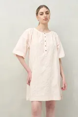 Vestido corto negro con bordado floral blanco, escote redondo con abotonadura frontal y mangas 3/4 abullonadas con pliegues en los hombros.