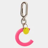 Llavero con dije en forma de letra A color rosado y pequeño dije circular amarillo con logo de la marca grabado. Incluye gancho metálico tipo mosquetón.