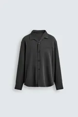 Camisa de manga larga color negro, confeccionada en tejido fluido con mezcla de viscosa. Presenta cuello bowling, bolsillo de vivo en el pecho y efecto lavado.