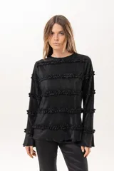 Blusa negra plisada de manga larga con detalles de volados horizontales en el frente y las mangas.